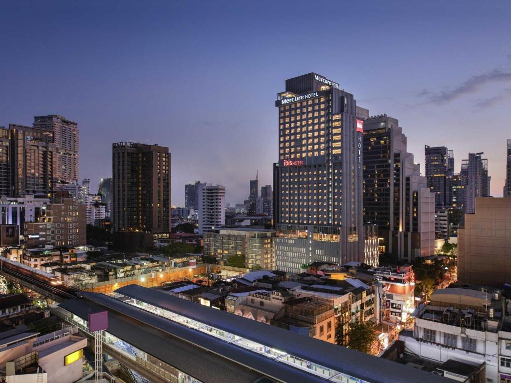 a city skyline with tall buildings and a train at Mercure Bangkok Sukhumvit 24 in Bangkok