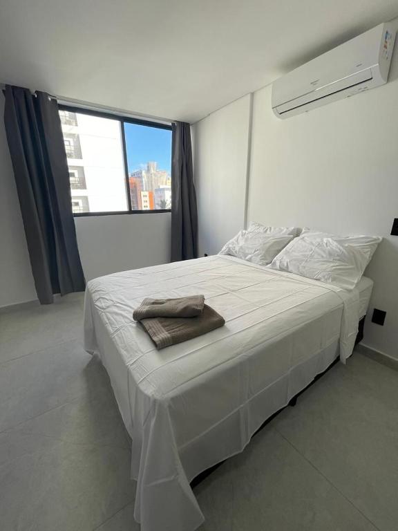 een wit bed in een kamer met een groot raam bij Flat em Intermares Beach in Cabedelo
