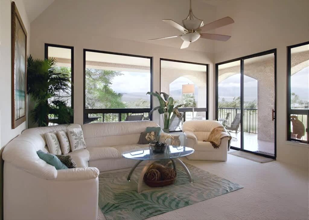 a living room with a white couch and a ceiling fan at Golf-view condo with golf discounts & lanai in Waikoloa