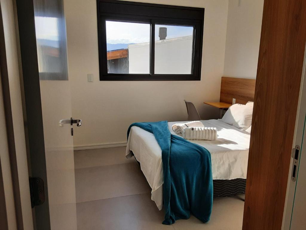 een slaapkamer met een bed met een blauwe deken erop bij Quarto e banheiro privativo pet friendly in Garopaba