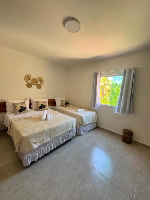 een slaapkamer met twee bedden en een raam bij Pousada Vila Mar Japaratinga in Japaratinga