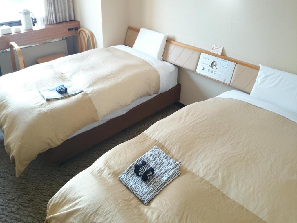 Deux lits dans une chambre d'hôtel avec deux sacs dessus dans l'établissement Hotel Furukawa Hills, à Osaki