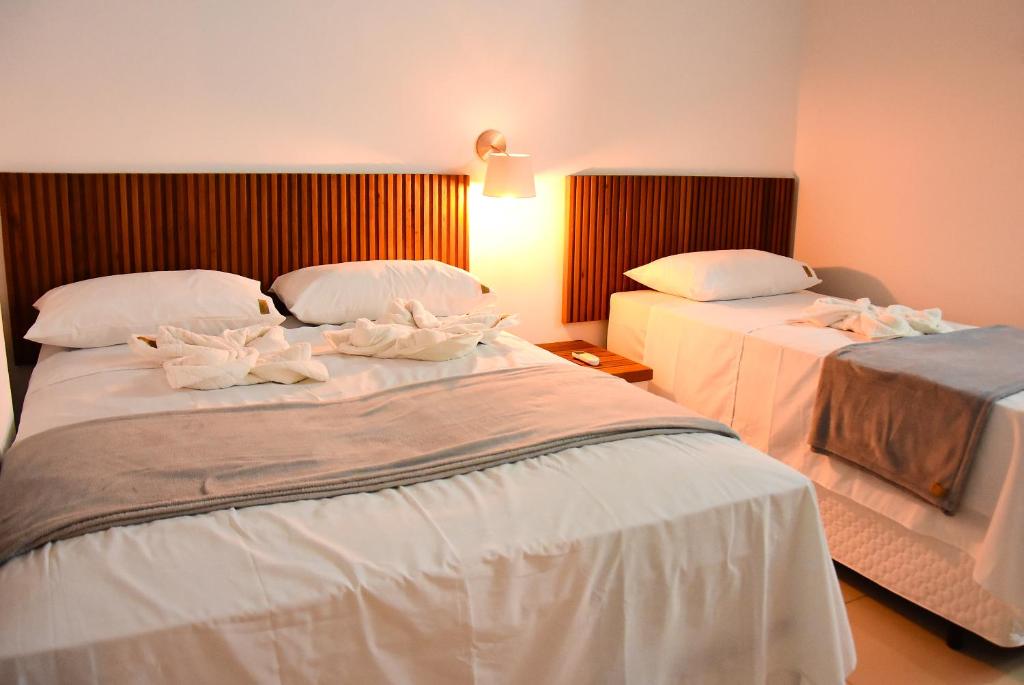 two beds in a hotel room with towels on them at Hotel Ipe in Barreirinhas