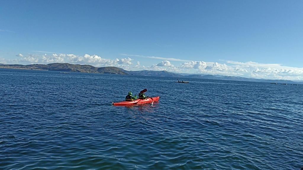 Twee mensen in een rode kajak op een groot wateroppervlak. bij SUMAQ WASI LLACHON casa de Juana in Llachon
