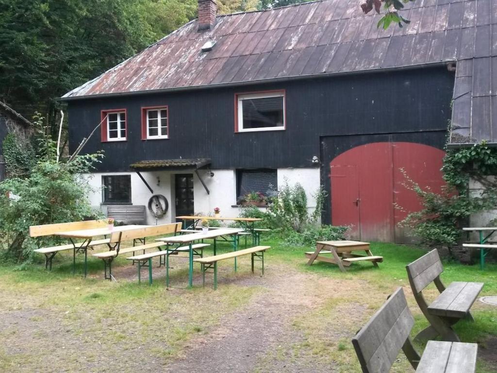 een zwart-wit gebouw met picknicktafels en banken bij Main building Neumühle in Lutzerath