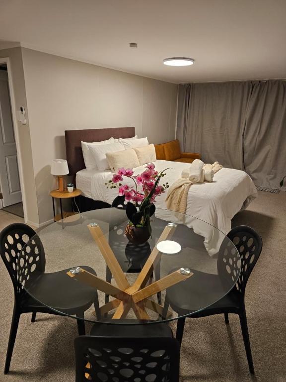 a room with a bed and a table with flowers on it at Private Guest suite Sleeps 4 in New Plymouth