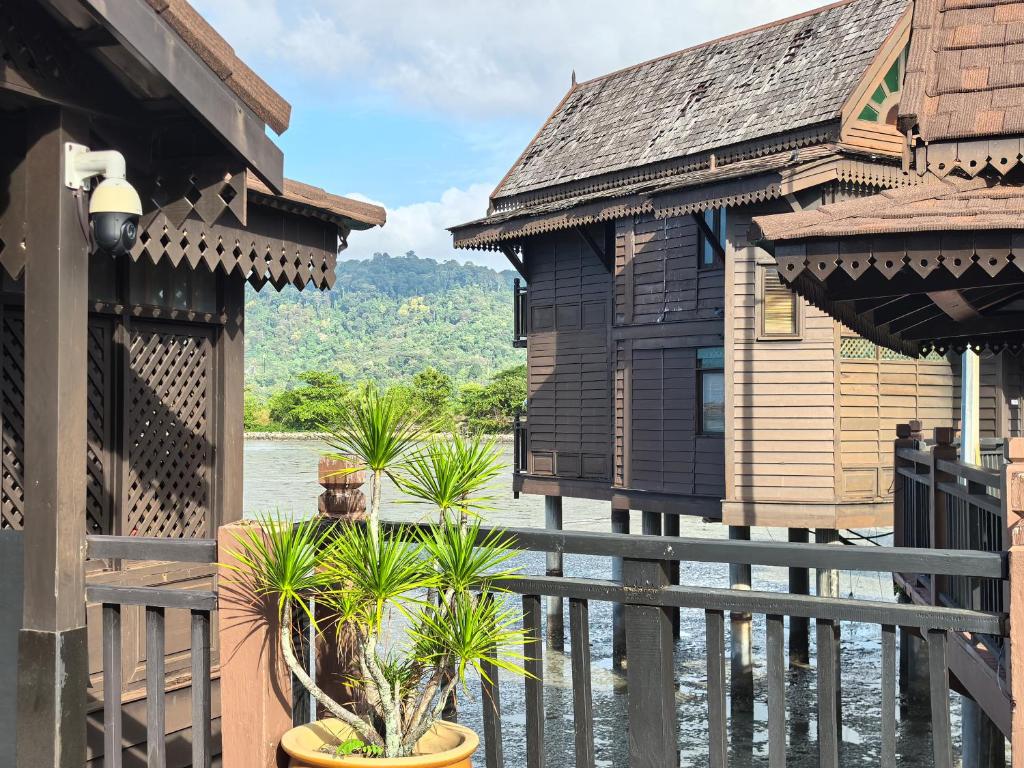een huis met een hek, wat bomen en water bij Langkawi Lagoon Floating Resort 01 in Langkawi Intl