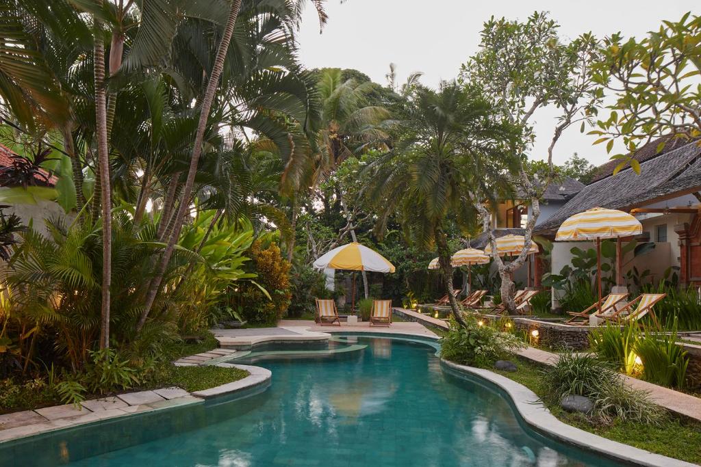 a pool at a resort with umbrellas and chairs at Shelter Island in Ubud