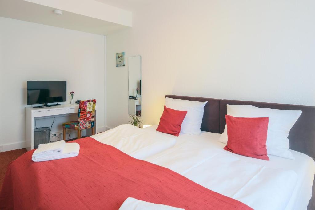 ein Schlafzimmer mit einem großen Bett mit roten und weißen Kissen in der Unterkunft Hotel Kleiner Markt in Saarlouis