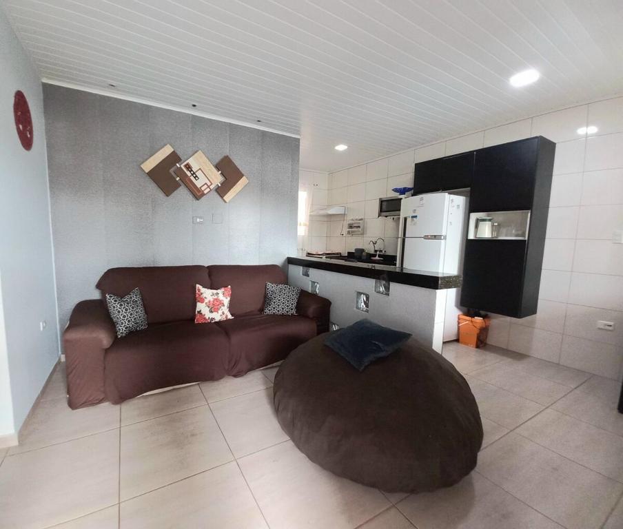 een woonkamer met een bruine bank en een keuken bij Casa Aconchegante in Guarujá