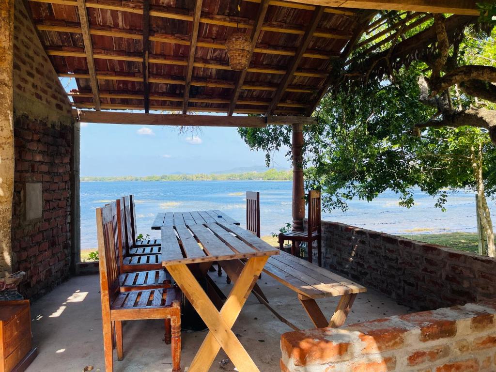 a picnic table and chairs on a porch with a view of the water at Can win Resort Yala in Tissamaharama