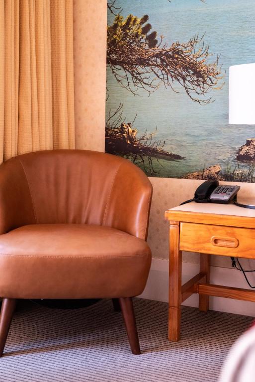 a brown chair sitting next to a table with a telephone at European Hotel in Perth