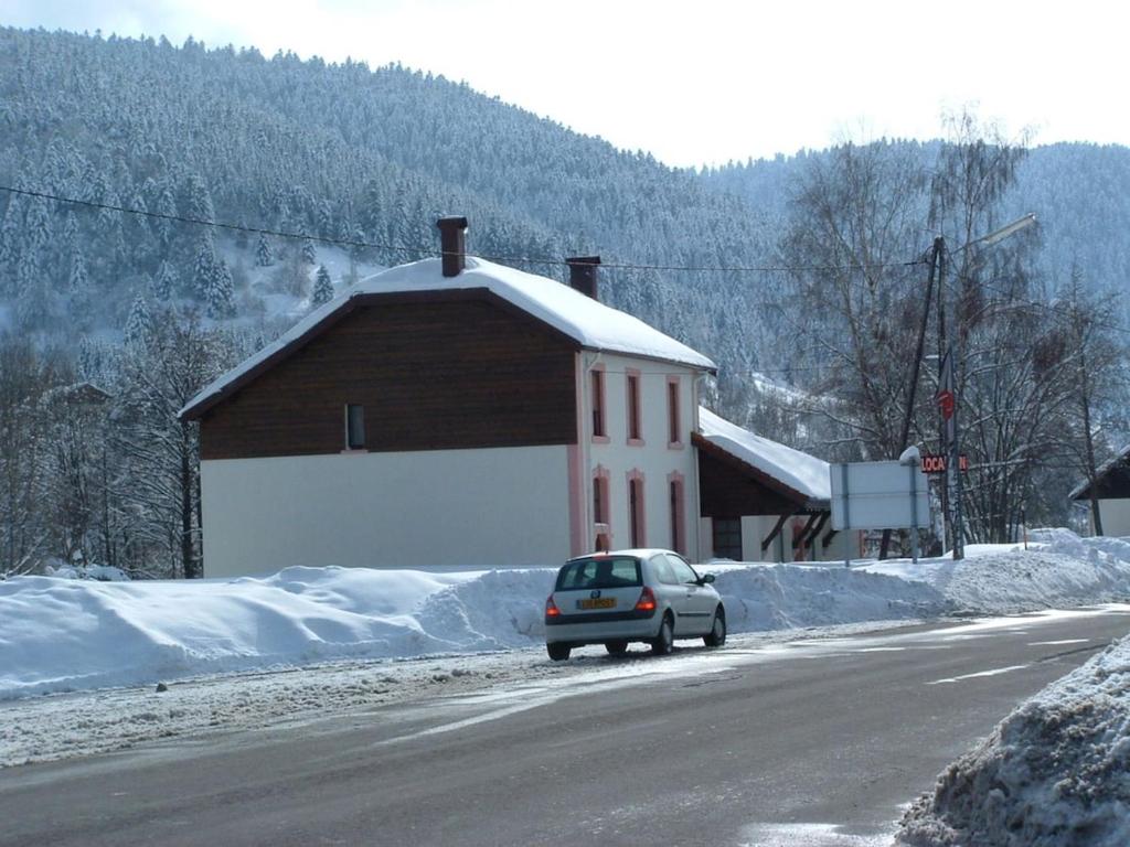une voiture garée sur le côté d'une route à côté d'un bâtiment dans l'établissement le flocon chaud sauna, à La Bresse