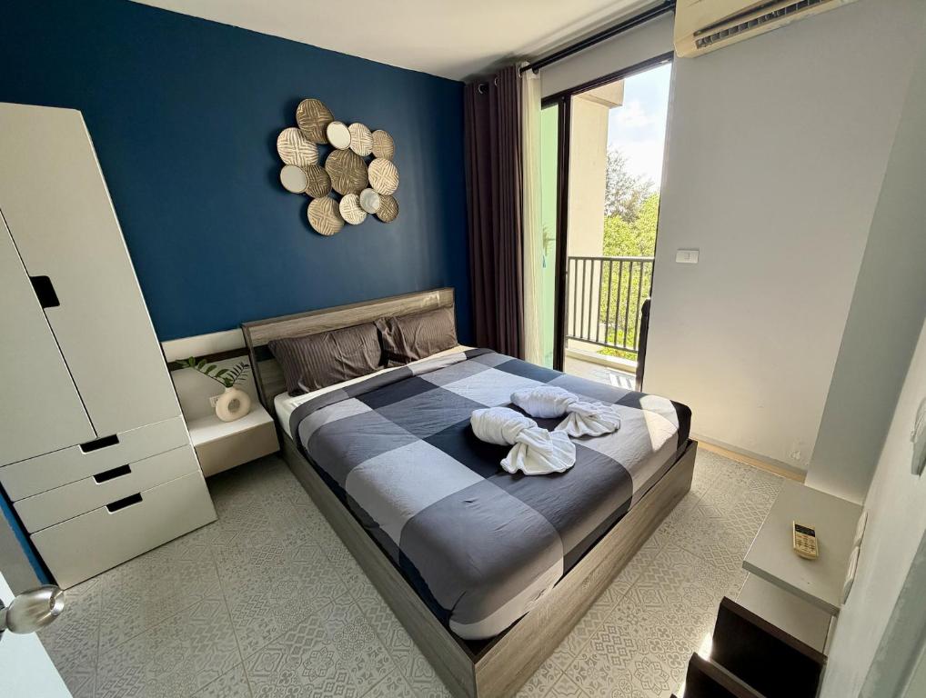 a bedroom with a bed with blue walls and a balcony at Z cape 1 two two in Ban Thalat Choeng Thale
