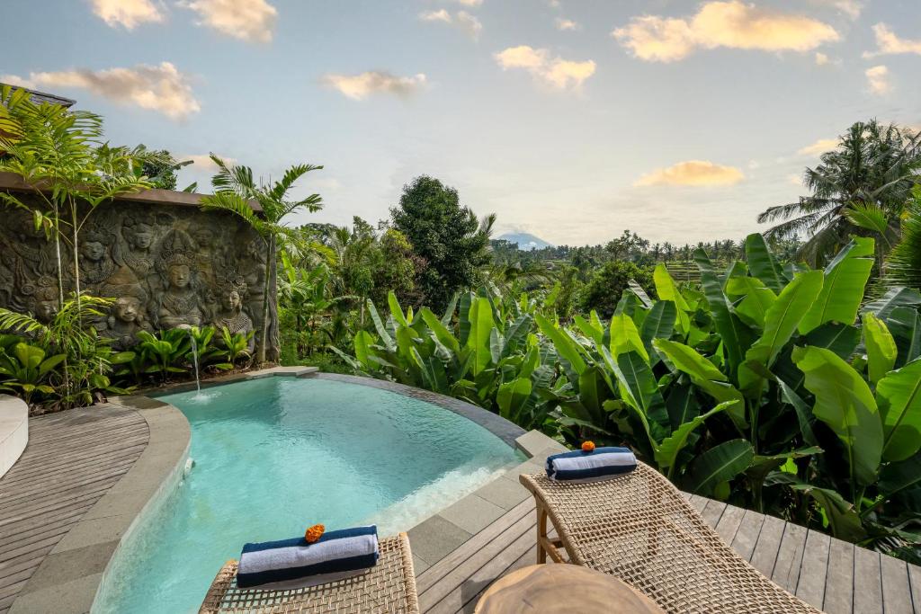 a resort pool with chairs and a mountain view at Govala Usada Ubud Villa in Ubud