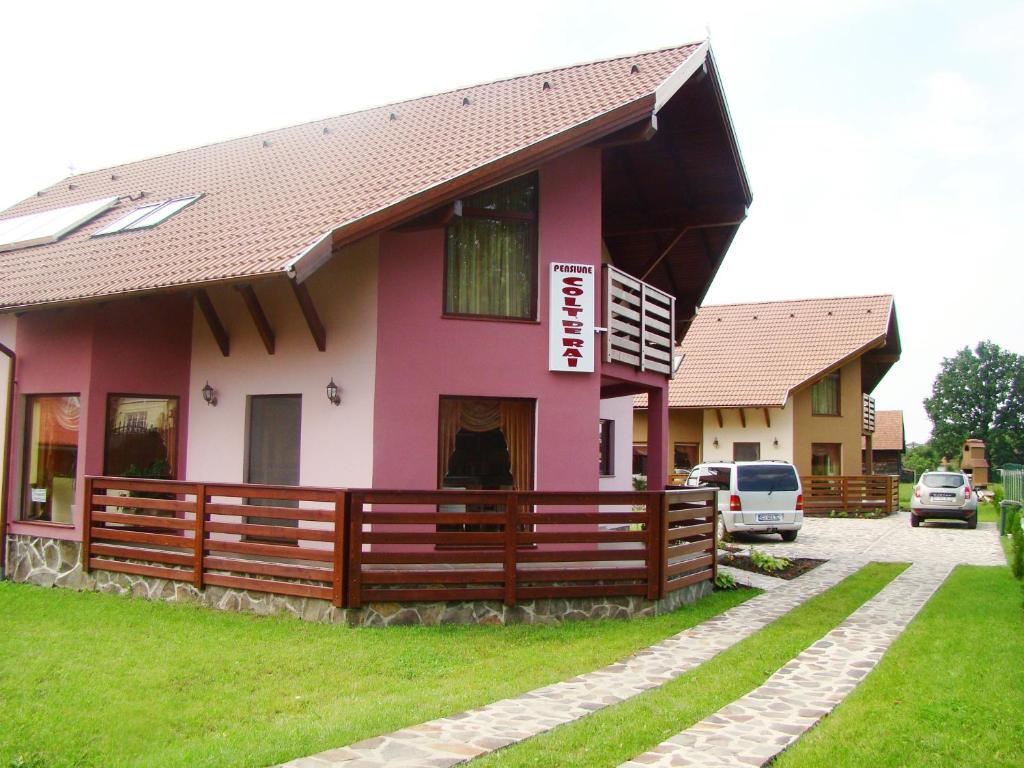 a pink house with a wooden fence in front of it at Colt de Rai in Covasna