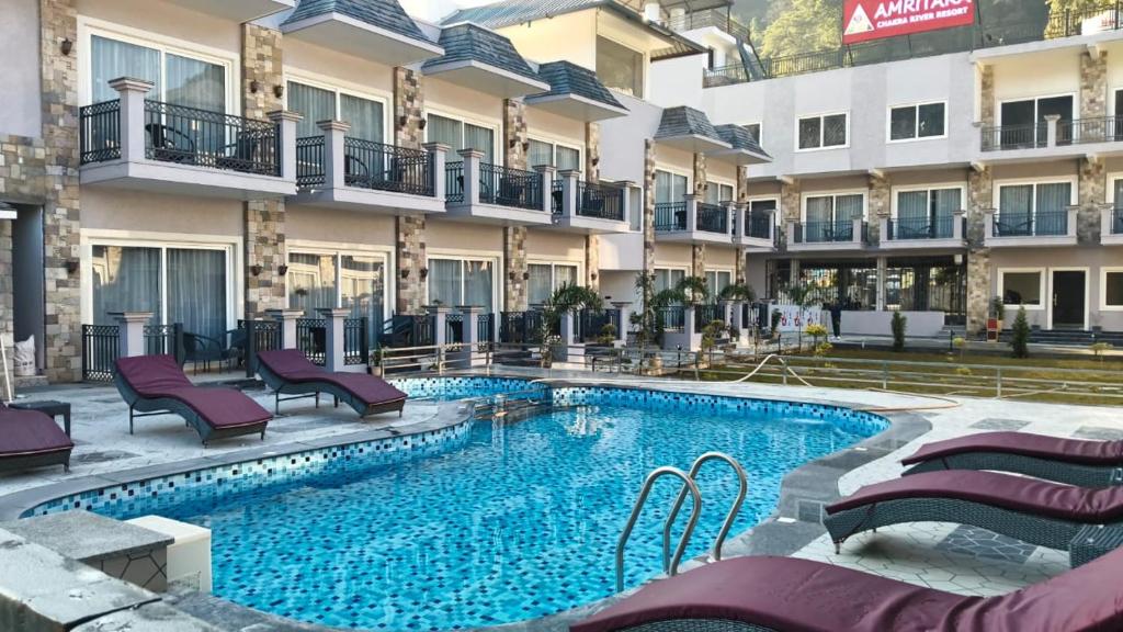 een hotelzwembad met paarse stoelen voor een gebouw bij Amritara Chakra River Resort in Mohan Chatti