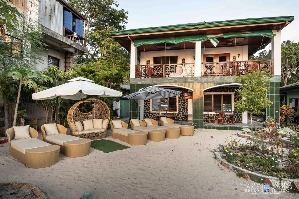 un patio con sedie e ombrelloni di fronte a un edificio di Morning Walsh Resort El Nido a El Nido