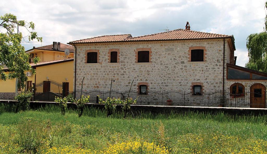 una vecchia casa in pietra con una recinzione in un campo di Nonno Domenico a Sassano