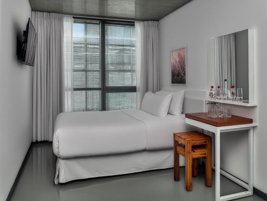 a white bedroom with a bed and a table at rõõm collective in Odiongan