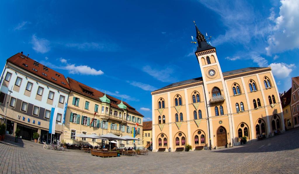 un bâtiment avec une tour d'horloge dans une rue dans l'établissement Hotel Müllerbräu, à Pfaffenhofen an der Ilm