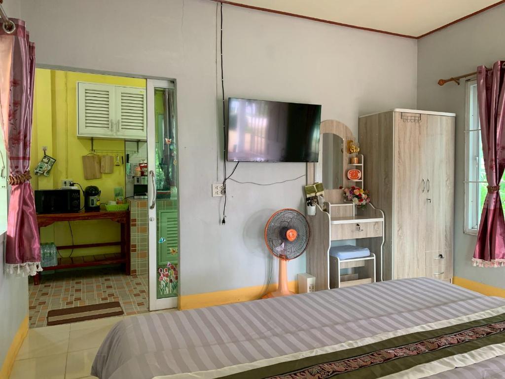ein Schlafzimmer mit einem Bett und einem Fernseher an der Wand in der Unterkunft Baan Suan Thada Thai บ้านสวนธาดา ไทย in Wang Nam Yen