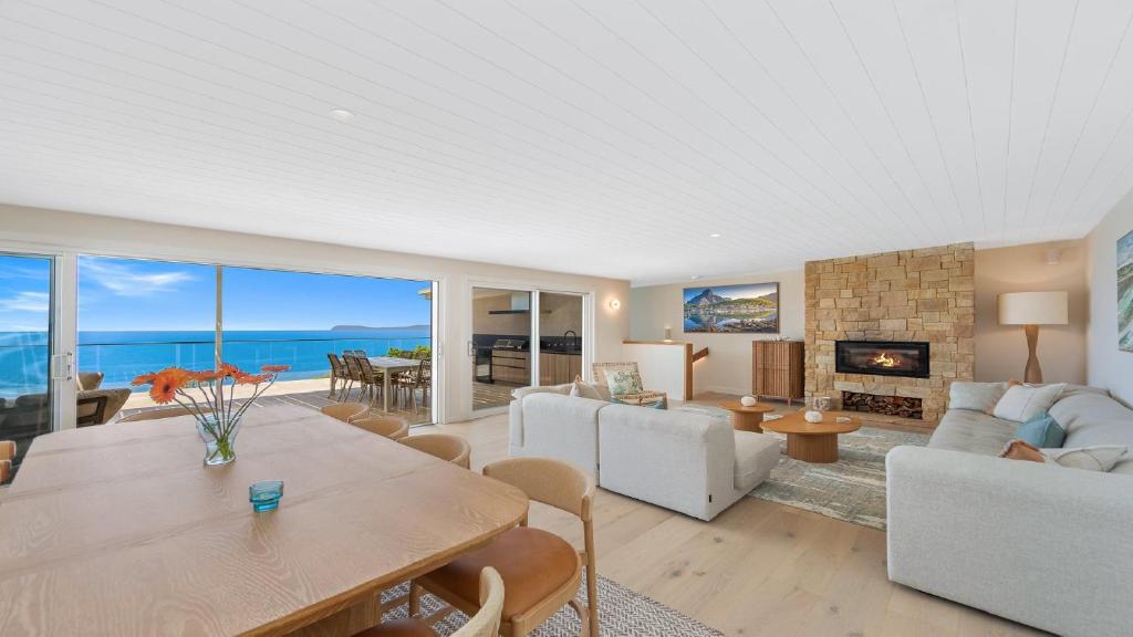 a living room with a table and a fireplace at 'Ocean Pearl' by HolidayCo in Hardys Bay