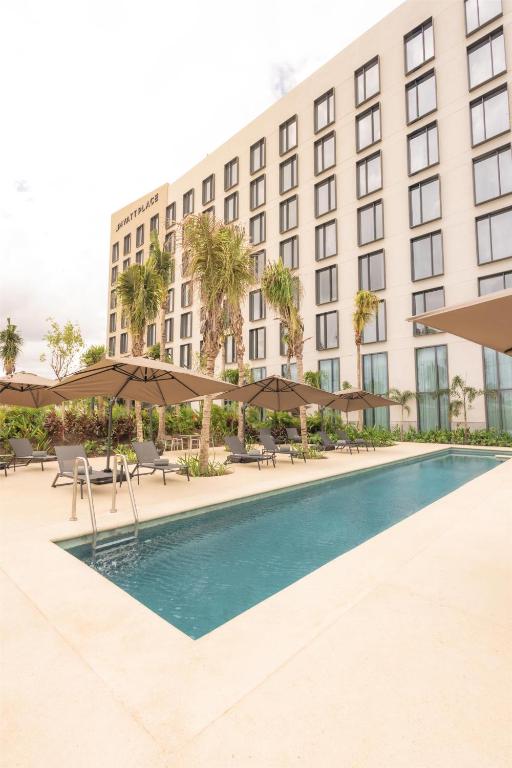 a hotel with a pool in front of a building at Hyatt Place Cancun Airport in Cancún