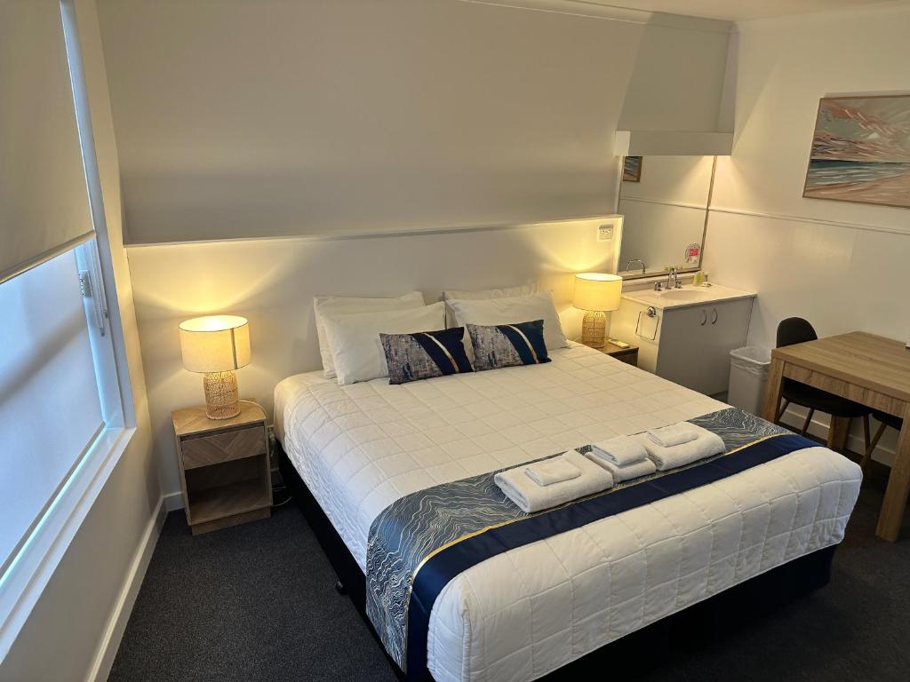 a bedroom with a bed with two towels on it at Bamboo Motor Inn in Lakes Entrance