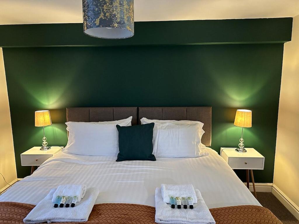 ein Schlafzimmer mit einem großen Bett mit einer grünen Wand in der Unterkunft Orange Lilly in Stroud with Free Parking in Stroud