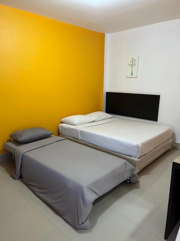 two beds in a room with a yellow wall at MyHome 3P Room in Ban Komo Sip Paet