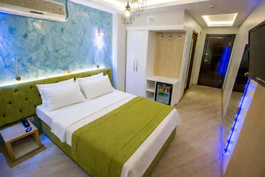 a bedroom with a large bed with a green blanket at Hotel Pera Capitol - Taksim & İstiklal in Istanbul
