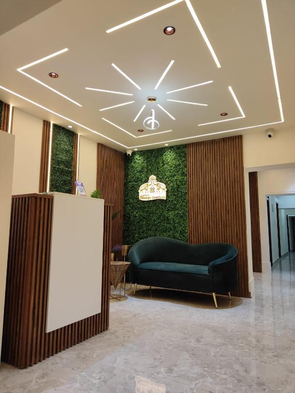 a lobby with a couch and a green wall at Nisarga Comforts in Chikmagalūr