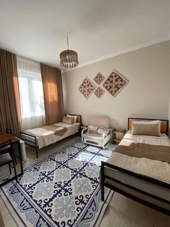een slaapkamer met 2 bedden en een tapijt bij Ala-Tor Guest House in Pokrovka