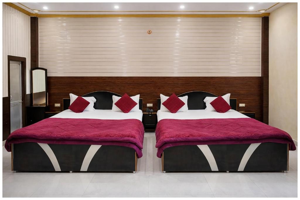 two beds with red pillows in a bedroom at HOTEL N ASHIYANA PALACE - Near Kasi Vishwanath Temple #Fully Air Conditioning #Wi-Fi #Parking -Best Hotel In Varanasi Book Now in Varanasi