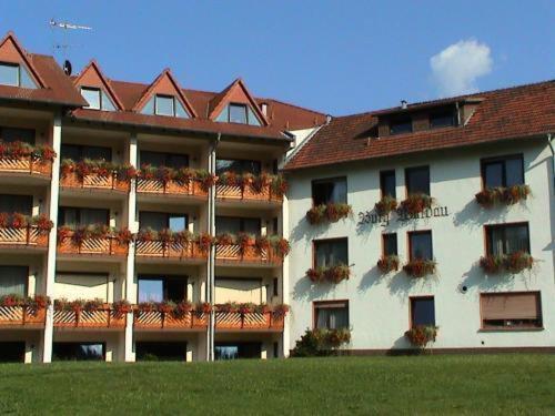 um grande edifício de apartamentos com flores nas varandas em Hotel Burg Waldau em Grasellenbach