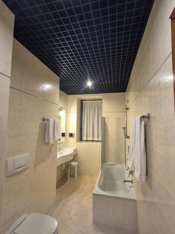 een badkamer met een bad, een toilet en een wastafel bij Hotel Excelsior Magenta in Magenta