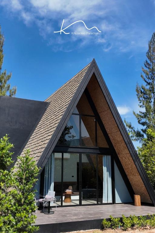 a house with a pitched roof with glass windows at Khunkhao Paradise Khao Yai in Ban Rai Khlong Sai