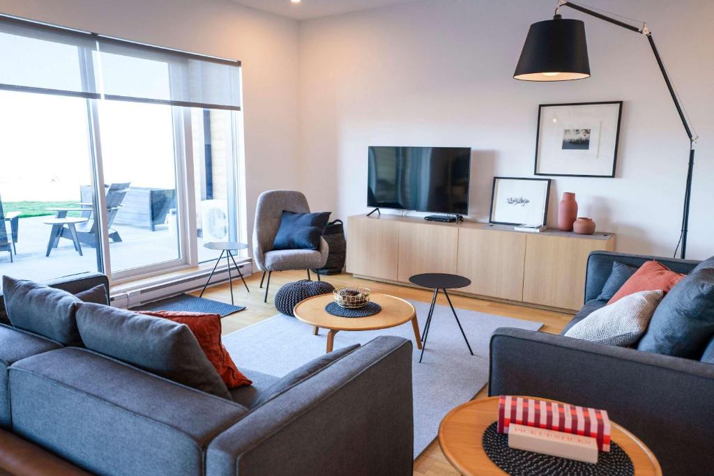 un salon avec deux canapés et une télévision dans l'établissement Luxury Condo on the Riverfront with Terrace, à Baie-Saint-Paul