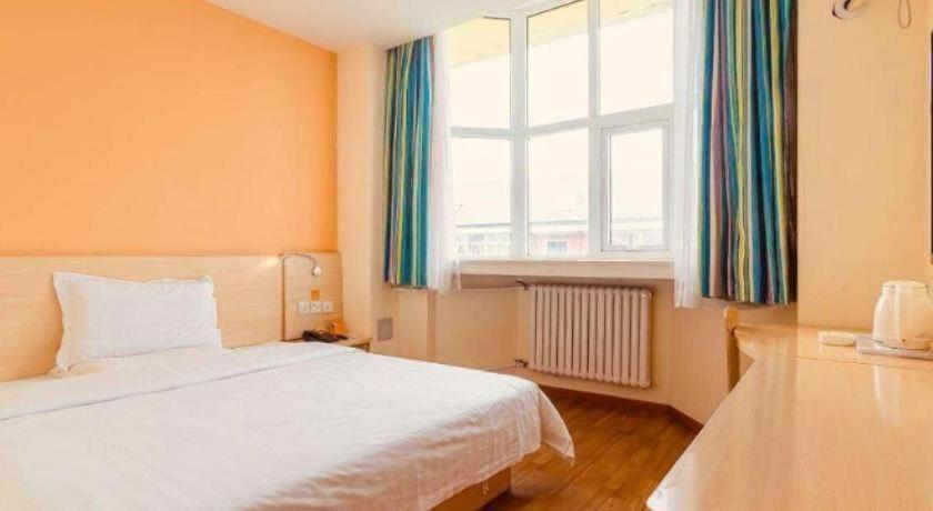 a bedroom with a white bed and a window at 7Days Inn Tianjin Fifth Avenue Youyi Road Branch in Tianjin