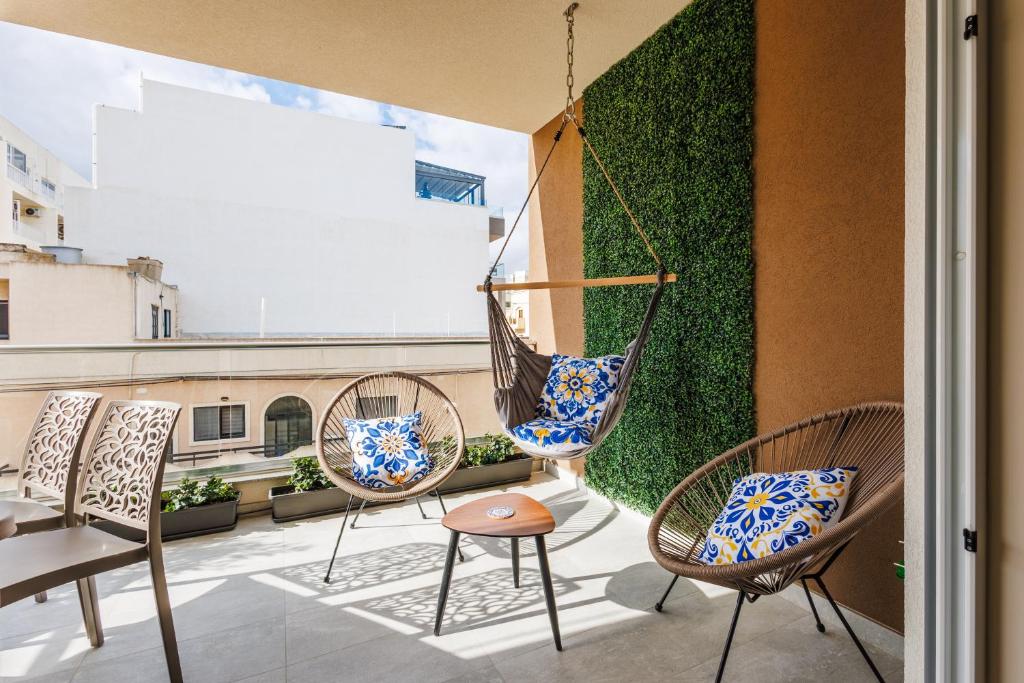 a patio with chairs and a hammock on a balcony at Stylish 2BR Retreat, Central Location, Few Steps from the Sea by QuickTrips in Marsaskala