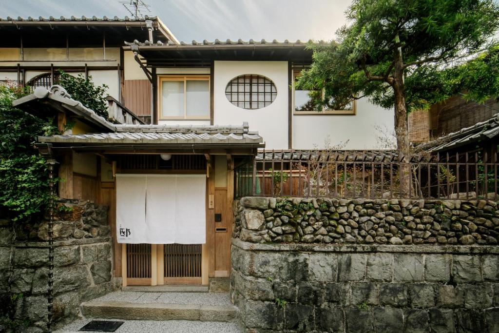 a house with a stone wall and a gate at 季楽 邸 清水 Kiraku Tei Kiyomizu in Kyoto
