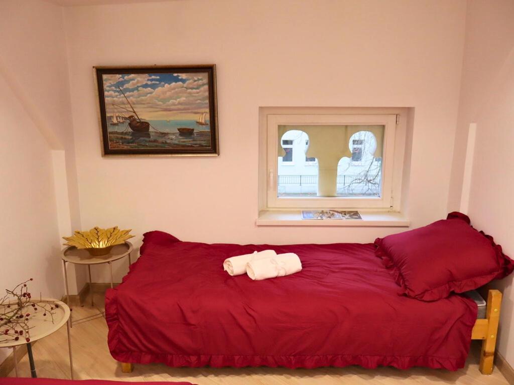 ein Schlafzimmer mit einem roten Bett und einem Fenster in der Unterkunft Rzymskie wakacje in Oppeln