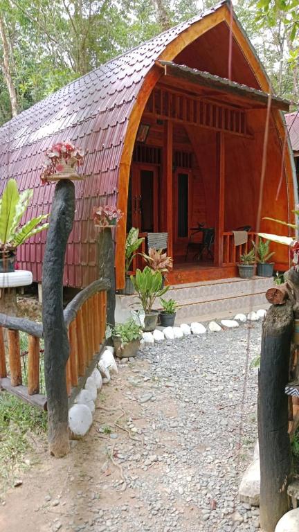 a small house with a red roof and a fence at Batu Katak Jungle River & Trekking in Bukit Lawang