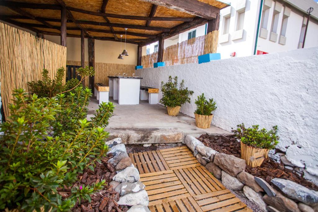 a patio with potted plants and a stone wall at The Pallet - Guest House in Santa Cruz