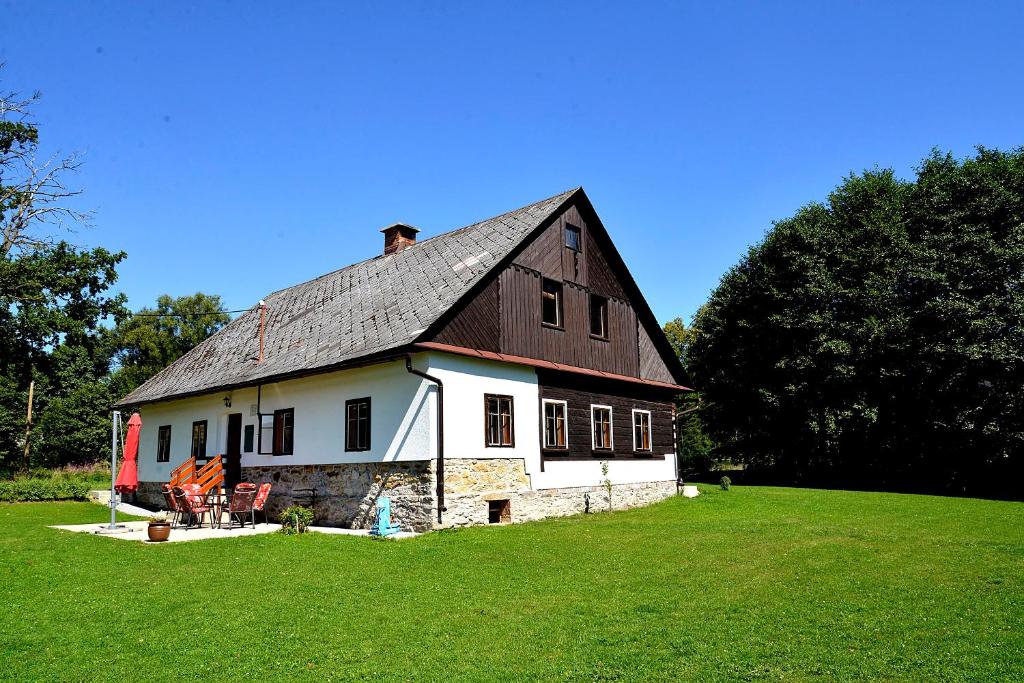 a large white barn with a black roof on a field at Ubytování Chalupa in Králíky