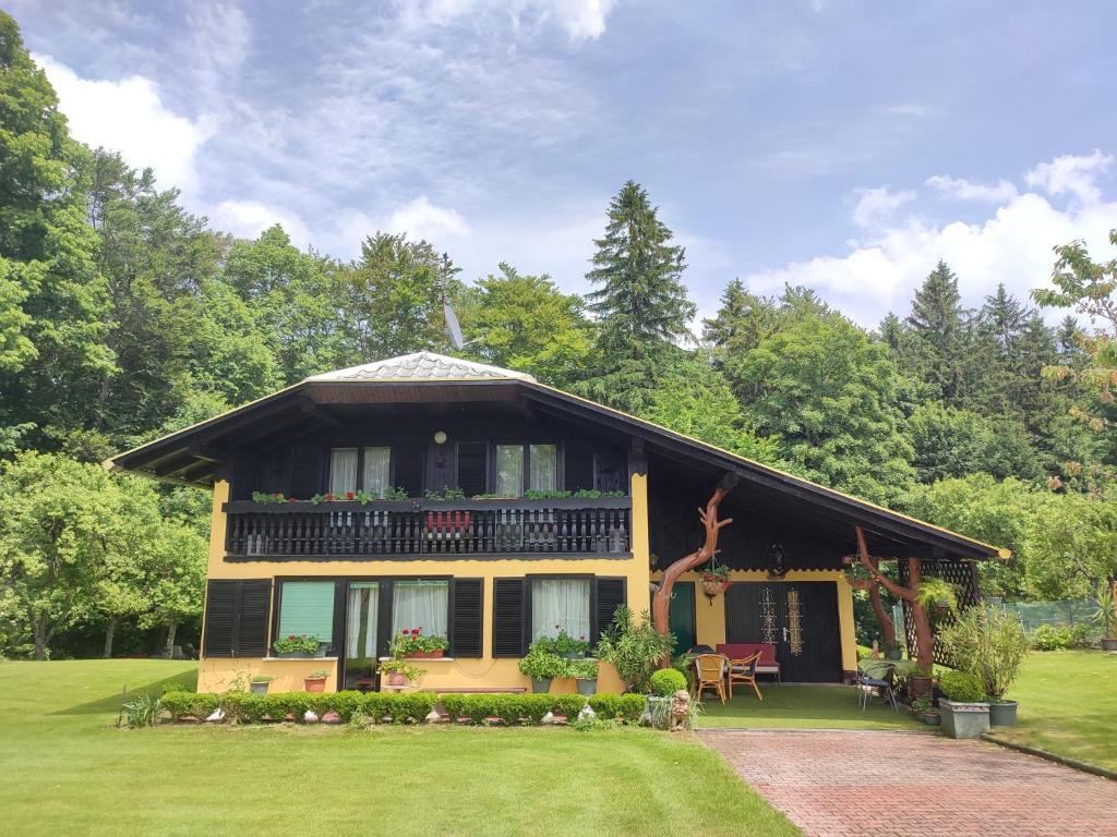 een geel huis met een balkon op een gazon bij Kopitnik cosy cabin in Dol pri Hrastniku