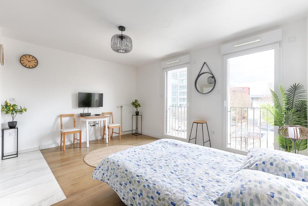 een witte slaapkamer met een bed en een tafel bij Ellington - Studio dans le quartier daffaires in Chatou