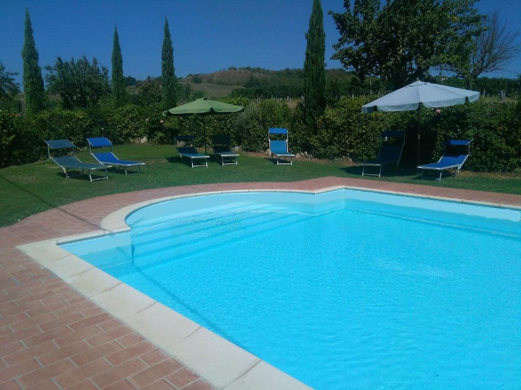 ein blauer Pool mit Stühlen und Sonnenschirmen in der Unterkunft Casa ai Carfini in Poggibonsi