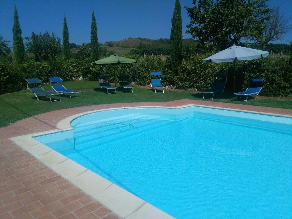 a blue swimming pool with chairs and umbrellas at Casa ai Carfini in Poggibonsi
